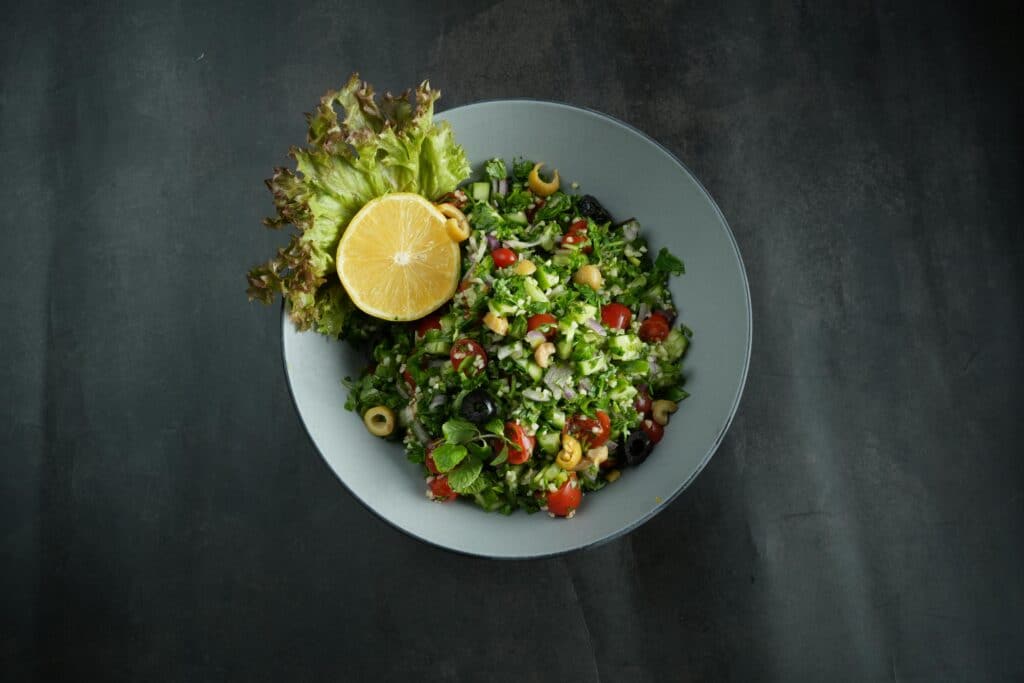 Top view of a vibrant Lebanese tabbouleh salad with fresh ingredients and a lemon garnish.