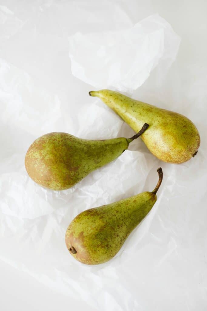 Three fresh pears on a white background showcasing minimalist still life art.